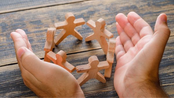 Piccole figure di legno che si tengono per mano simbolo di Inclusione sociale